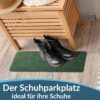 POETGRUN-025-060_20 Schmale, grüne Schuhparkplatz-Fußmatte mit schwarzen Stiefeln vor einer Holzbank.