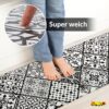 GANT09_20 Weiche, schwarz-weiß gemusterte Anti-Ermüdungsmatte mit Person auf Fliesenoptik.