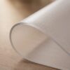 ANRO_mattierte_Folie_2mm_04-jpg Gerollte, matte Tischschutzfolie mit 2 mm Stärke auf Holzoberfläche.